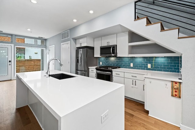 2002 E 7th St Unit 204, Austin, TX 78702 - kitchen featuring appliances with stainless steel finishes, a sink, light wood finished floors, white cabinets, and recessed lighting