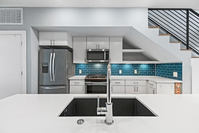 2002 E 7th St Unit 204, Austin, TX 78702 - kitchen featuring appliances with stainless steel finishes, a sink, light countertops, white cabinetry, and decorative backsplash