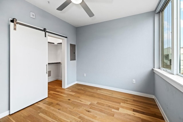 2002 E 7th St Unit 204, Austin, TX 78702 - unfurnished bedroom with multiple windows, electric panel, a barn door, and light wood-style flooring