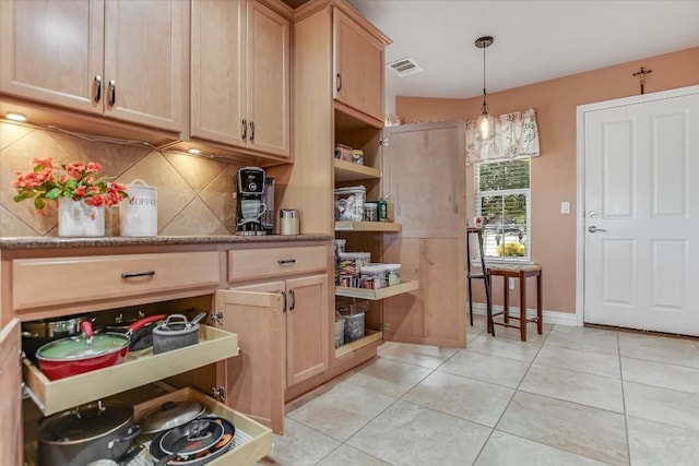 kitchen with hanging light fixtures, light brown cabinetry, light stone countertops, decorative backsplash, and light tile patterned floors