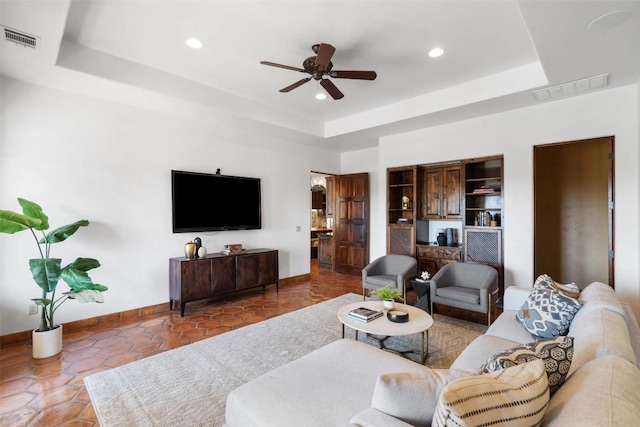 living area featuring visible vents, ceiling fan, baseboards, and a raised ceiling