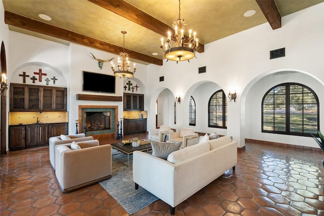 living room with beamed ceiling, arched walkways, an inviting chandelier, and visible vents