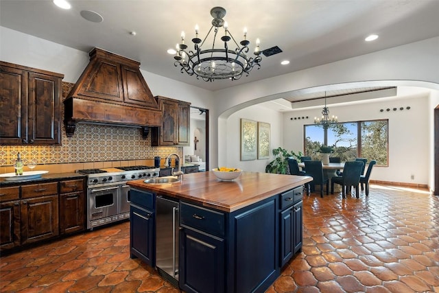 kitchen with custom range hood, premium stove, arched walkways, and a notable chandelier