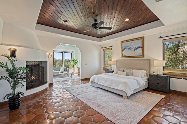 bedroom featuring a tray ceiling, baseboards, multiple windows, and wooden ceiling