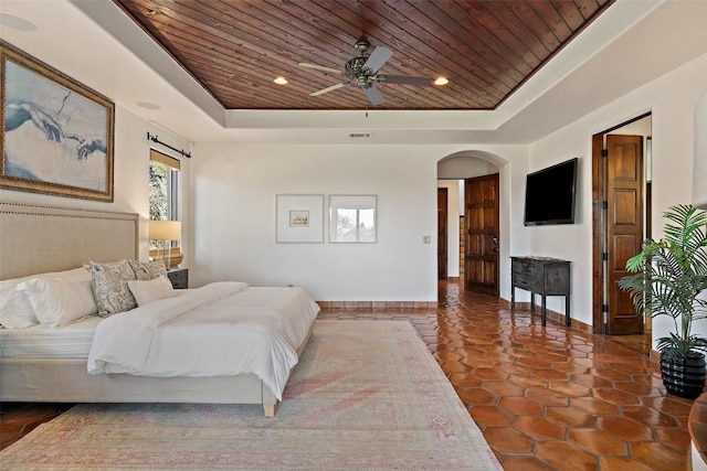 bedroom featuring a tray ceiling, baseboards, and wooden ceiling