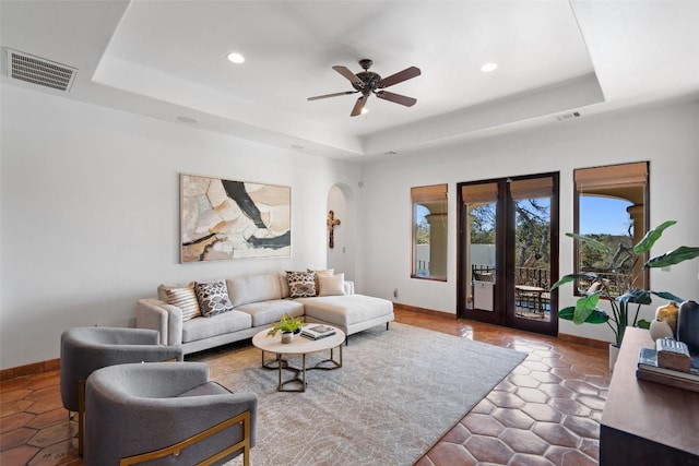 living area featuring recessed lighting, visible vents, a tray ceiling, and baseboards