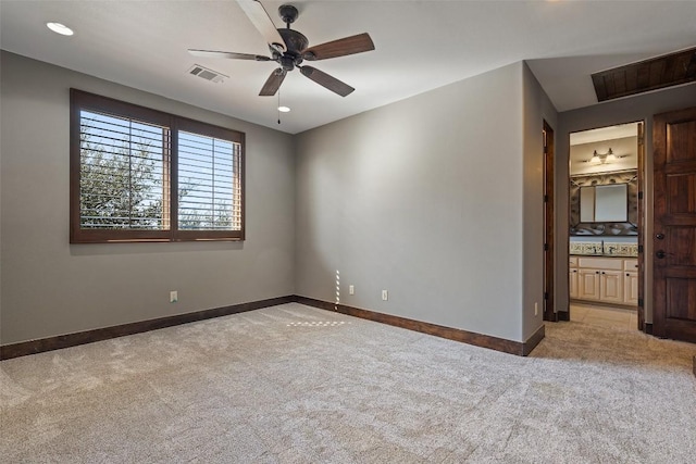 spare room with visible vents, baseboards, a ceiling fan, and light carpet