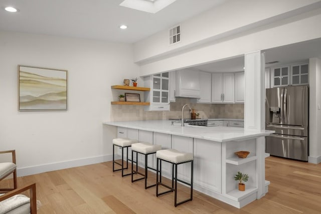 1907 Casa Grande Dr, Austin, TX 78733 - kitchen with stainless steel fridge, open shelves, custom exhaust hood, a peninsula, and decorative backsplash