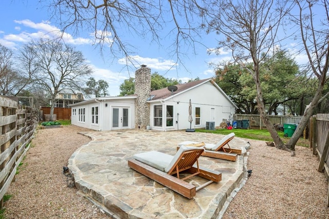 1907 Casa Grande Dr, Austin, TX 78733 - back of property with french doors, a patio, a fenced backyard, and a chimney