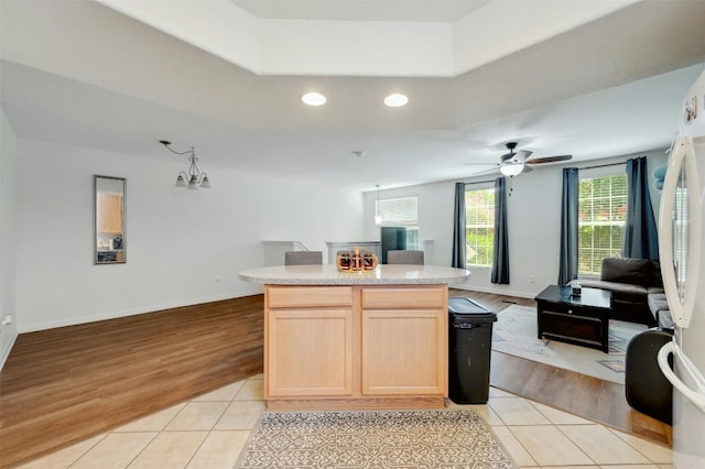 kitchen with light brown cabinets, a center island, and light tile patterned floors