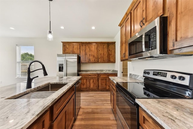 112 Callie St, Smithville, TX 78957 - kitchen with brown cabinets, a sink, light stone countertops, pendant lighting, and appliances with stainless steel finishes