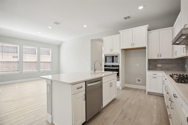 kitchen with a center island with sink, stainless steel appliances, and white cabinetry