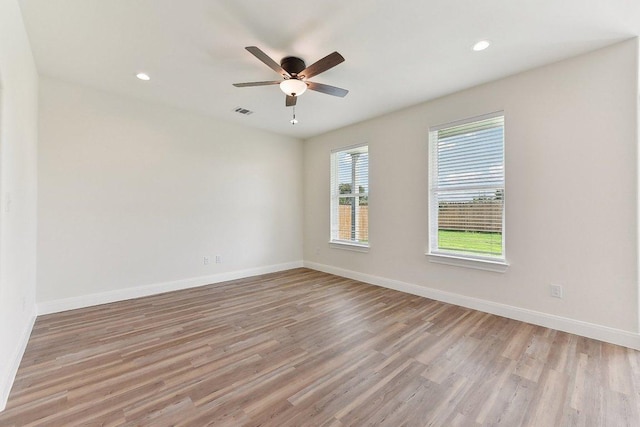 empty room featuring light wood-style floors, visible vents, baseboards, and ceiling fan