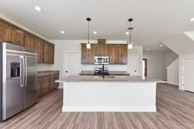 kitchen featuring an island with sink, stainless steel appliances, visible vents, a sink, and light wood-style flooring