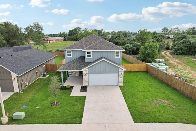 traditional-style house featuring a front lawn, driveway, fence, and stone siding