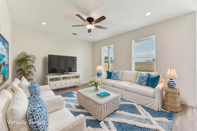 living room featuring wood finished floors, visible vents, a ceiling fan, and baseboards