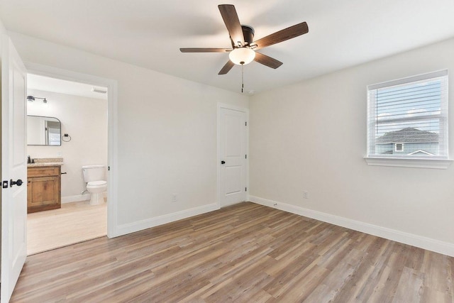 unfurnished bedroom with ensuite bath, baseboards, light wood-style floors, and a ceiling fan