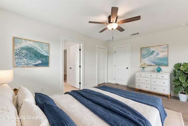 bedroom with baseboards, wood finished floors, visible vents, and a ceiling fan