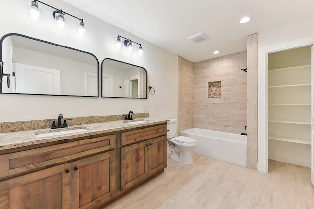 bathroom featuring double vanity, wood finished floors, toilet, and a sink