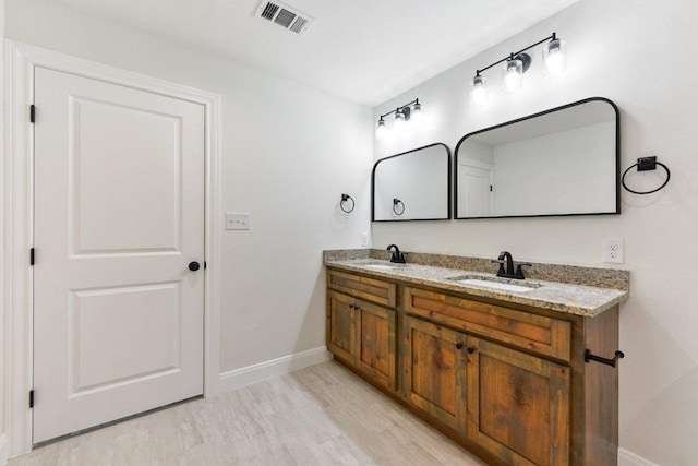 bathroom featuring baseboards, wood finished floors, visible vents, and a sink