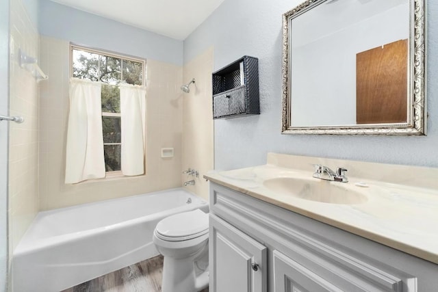 full bathroom with vanity, tiled shower / bath, toilet, and hardwood / wood-style floors