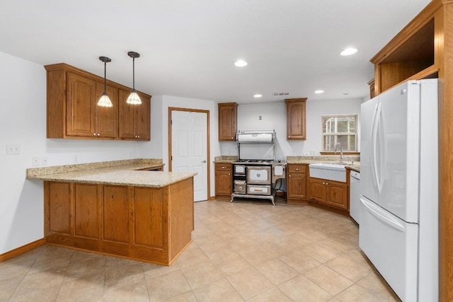 kitchen with white appliances, sink, decorative light fixtures, kitchen peninsula, and light stone countertops