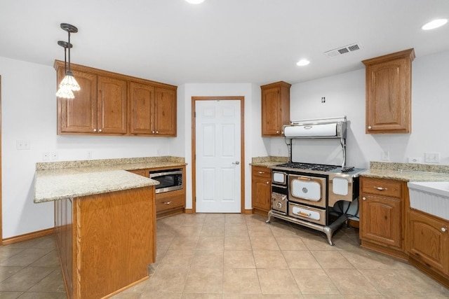 kitchen featuring stainless steel microwave, pendant lighting, light stone countertops, and ventilation hood