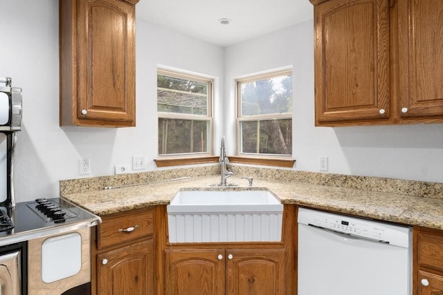 kitchen featuring sink, white dishwasher, and light stone counters