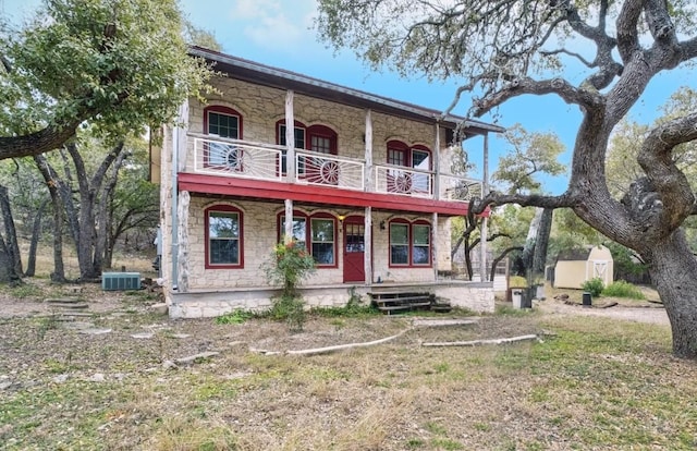 view of front facade featuring cooling unit, a storage unit, and a porch