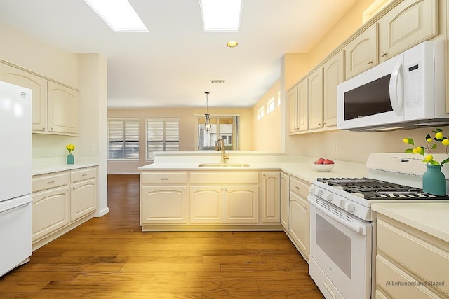 216 Whispering Wind Dr, Georgetown, TX 78633 - kitchen featuring white appliances, a peninsula, light wood-style floors, light countertops, and hanging light fixtures
