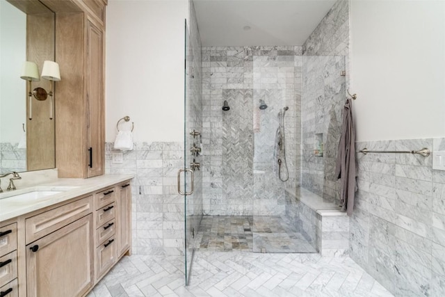 bathroom featuring a shower with door, tile walls, and vanity