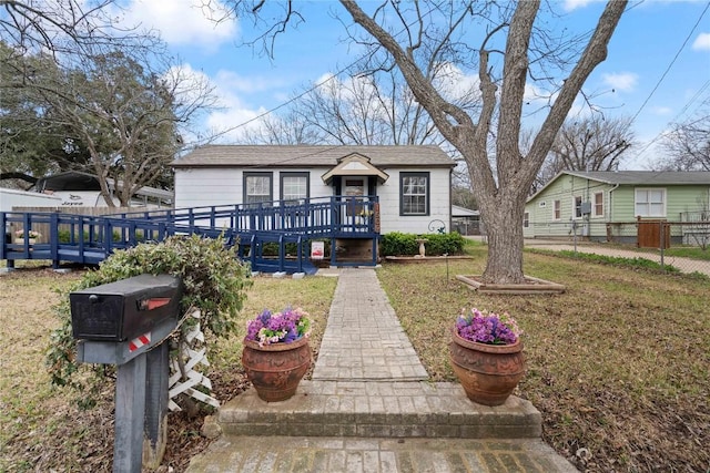 view of front facade featuring a wooden deck and a front yard