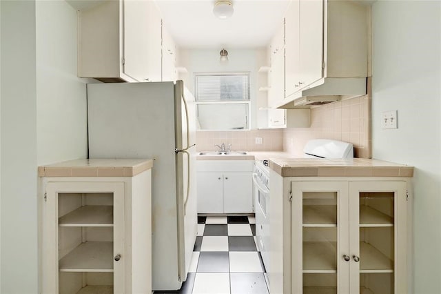 kitchen featuring white appliances, tile counters, decorative backsplash, sink, and white cabinetry