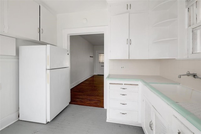 kitchen with white fridge, white cabinetry, sink, and decorative backsplash