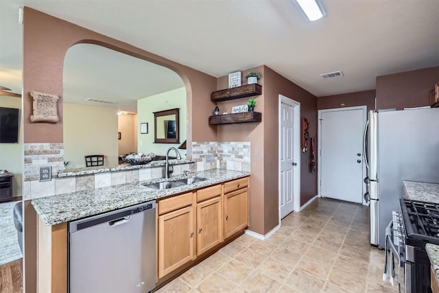 kitchen featuring sink, light stone counters, stainless steel appliances, kitchen peninsula, and tasteful backsplash