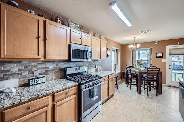 kitchen with stainless steel appliances, decorative light fixtures, a notable chandelier, light stone counters, and decorative backsplash