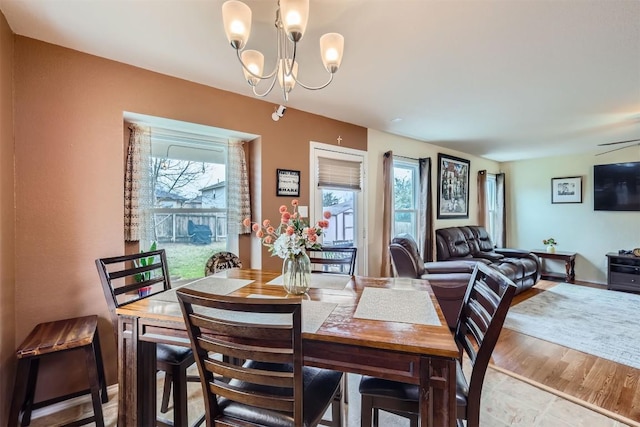 dining area with hardwood / wood-style floors, plenty of natural light, and a notable chandelier