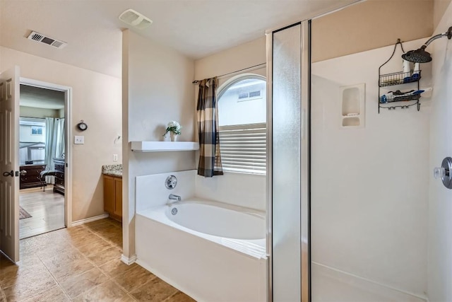 bathroom with tile patterned floors, independent shower and bath, vanity, and a wealth of natural light