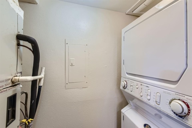 laundry area with stacked washing maching and dryer, electric panel, and laundry area