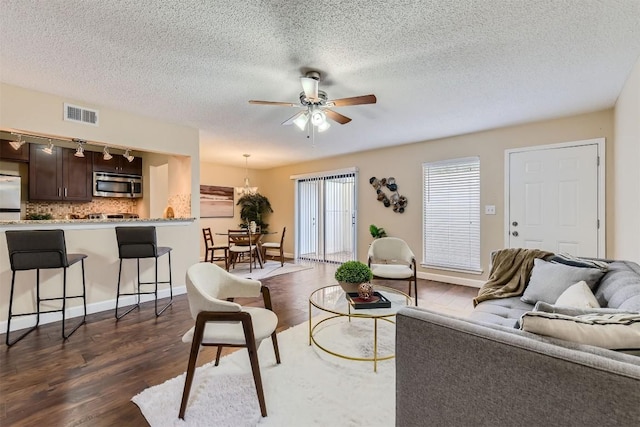 living area with dark wood-type flooring, visible vents, a textured ceiling, and a ceiling fan