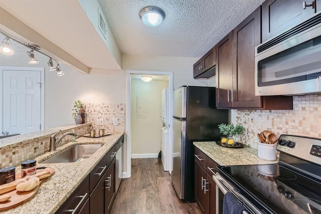 kitchen featuring wood finished floors, a sink, dark brown cabinets, appliances with stainless steel finishes, and light stone countertops