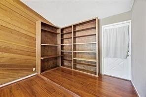 interior space with dark hardwood / wood-style flooring and wood walls