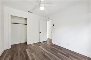 unfurnished bedroom with ceiling fan, dark wood-type flooring, and a closet