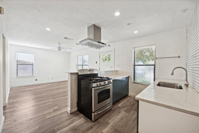 300 Tilbury Ln, Austin, TX 78745 - kitchen featuring stainless steel gas range, island exhaust hood, a textured ceiling, wood finished floors, and recessed lighting