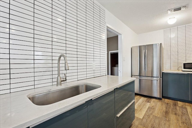 300 Tilbury Ln, Austin, TX 78745 - kitchen featuring freestanding refrigerator, gray cabinetry, white microwave, light wood-type flooring, and a textured ceiling