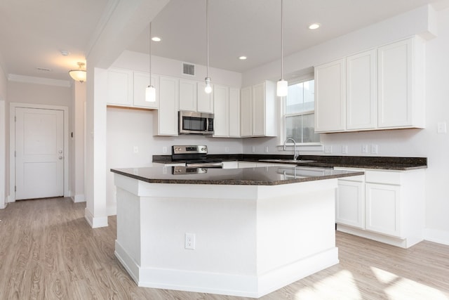 kitchen with appliances with stainless steel finishes, white cabinets, and a center island