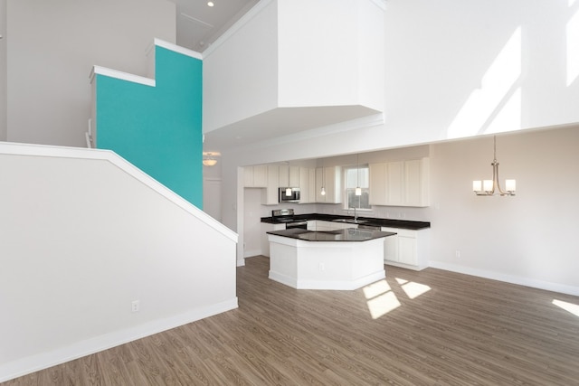 kitchen with an inviting chandelier, white cabinetry, pendant lighting, stainless steel appliances, and a high ceiling