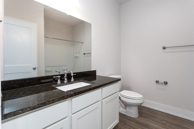 bathroom with hardwood / wood-style floors, vanity, toilet, and walk in shower