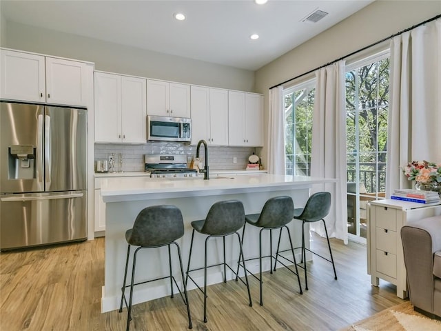 3809 Valley View Rd Unit 1, Austin, TX 78704 - kitchen featuring stainless steel appliances, light wood-style flooring, light countertops, backsplash, and white cabinetry