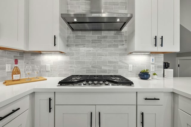 kitchen with wall chimney range hood, white cabinetry, and stainless steel gas cooktop